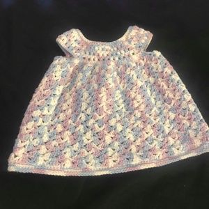 A handmade crocheted multi-color baby dress.